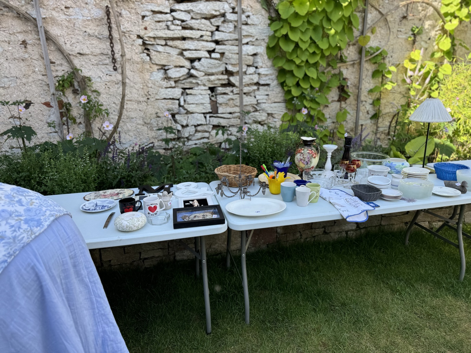 Blandade loppisfynd på bord i innegården